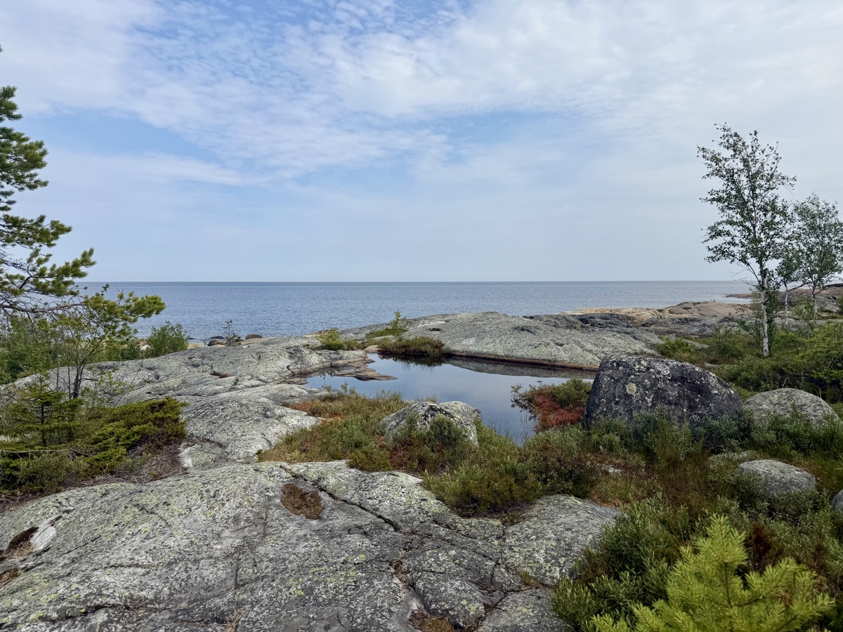 Felsküste mit einem kleinen Tümpel im Vordergrund und Blick über die Schären aufs Meer
