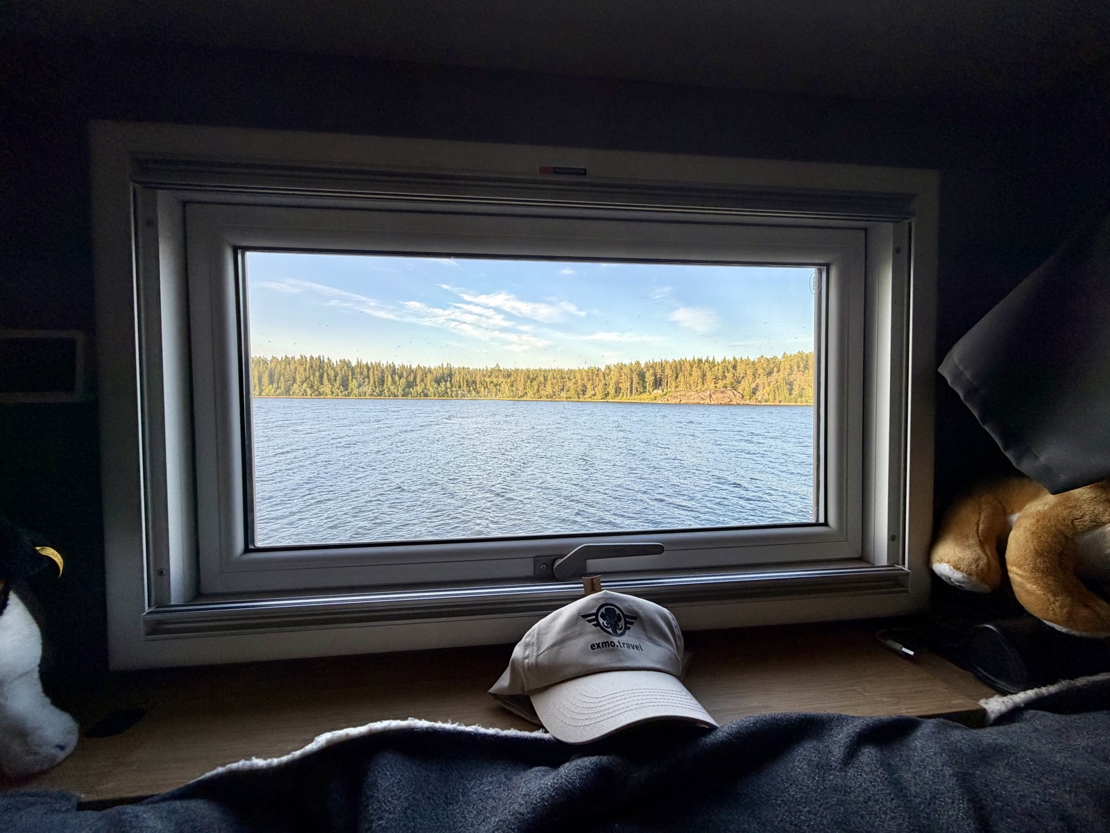 Blick aus dem Fenster am Tisch auf die Bucht und den Wald am anderen Ufer