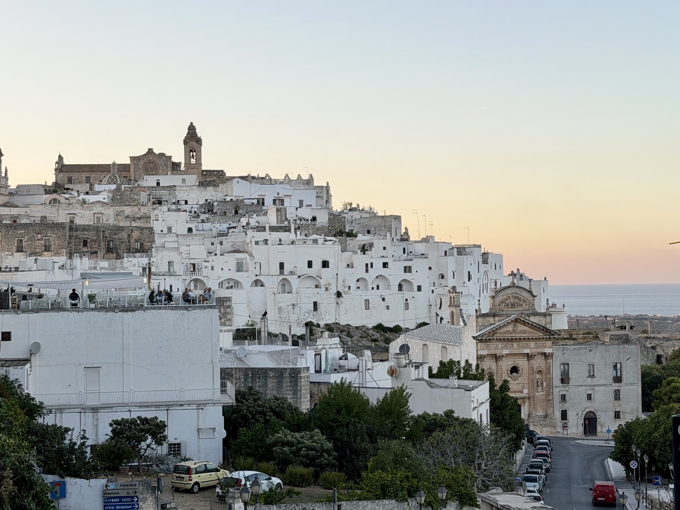 Die weißen Häuser von Ostuni im Abendlicht auf einem Hügel, oben ein Kirchturm
