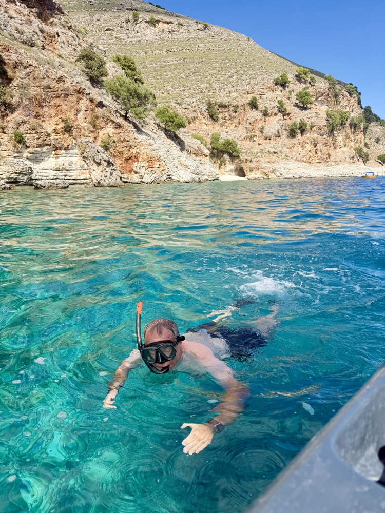 Schnorchler im klaren, türkisfarbenen Wasser vor einer felsigen Küste