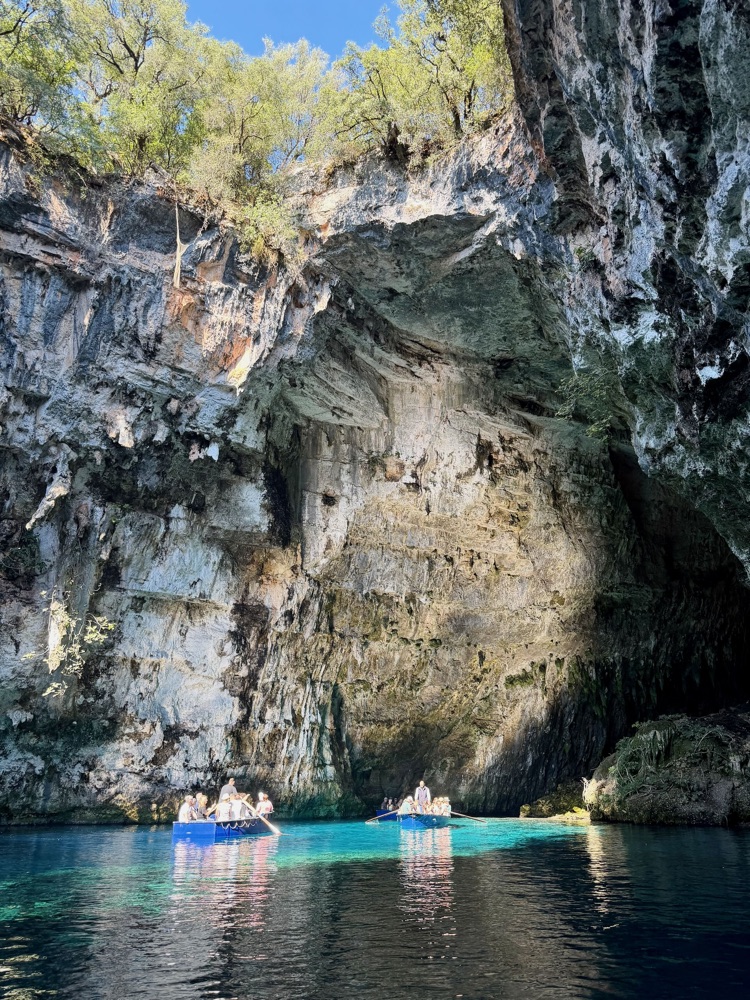 Hohe Felswand der Höhle mit zwei Booten auf türkisfarbenem Wasser