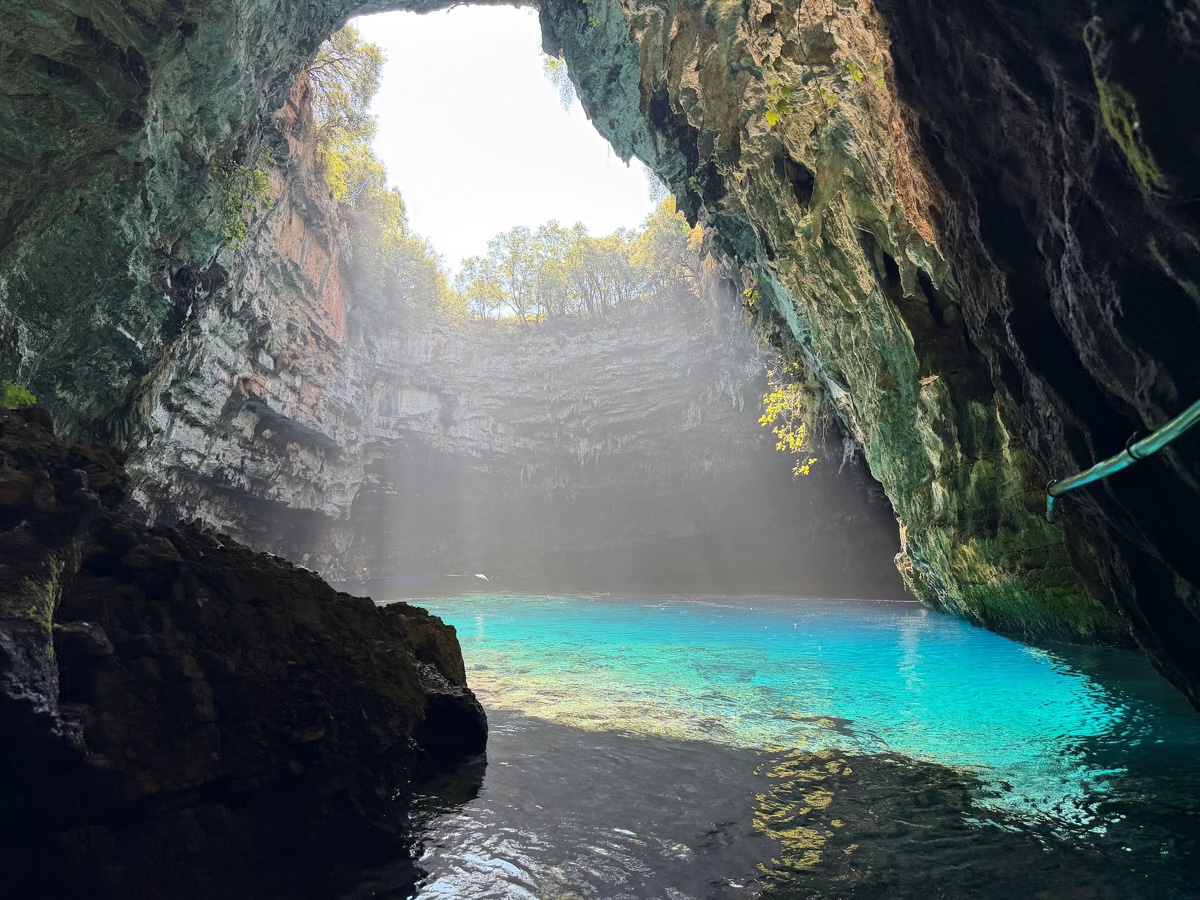 Sonnenstrahlen fallen durch die Öffnung der Höhle auf türkisfarbenes Wasser
